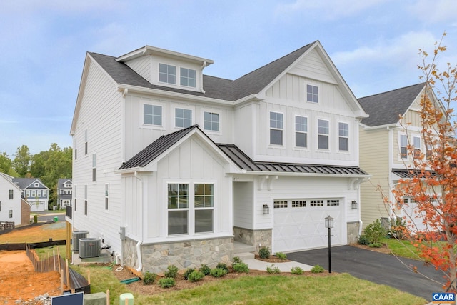 view of front facade with an attached garage, stone siding, metal roof, aphalt driveway, and a standing seam roof