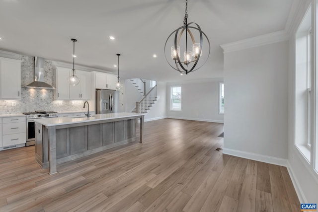 kitchen featuring stainless steel appliances, wall chimney range hood, a kitchen island with sink, backsplash, and baseboards