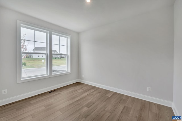 empty room featuring baseboards, visible vents, and wood finished floors