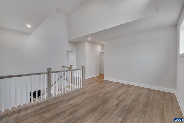 unfurnished room with baseboards, recessed lighting, a towering ceiling, and wood finished floors