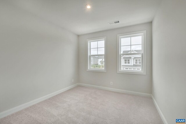 unfurnished room featuring visible vents, baseboards, and light carpet