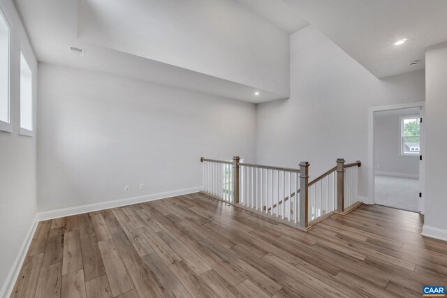 additional living space featuring baseboards, visible vents, a towering ceiling, and wood finished floors