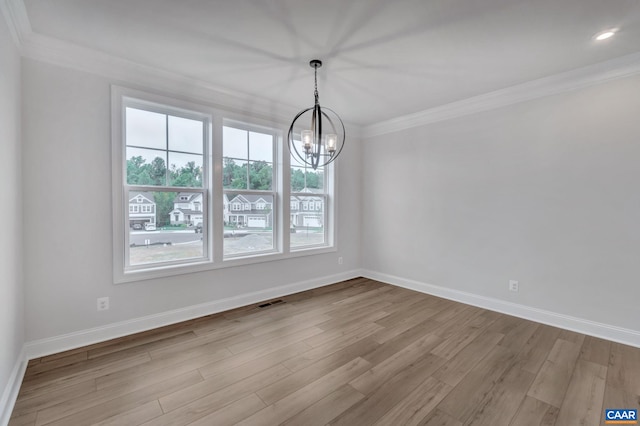 unfurnished dining area featuring baseboards, a notable chandelier, crown molding, and wood finished floors