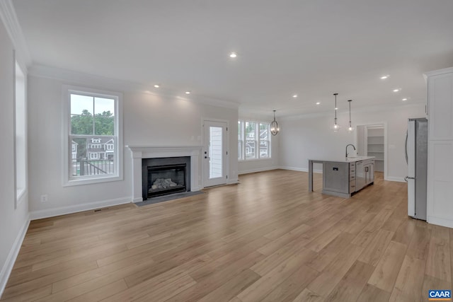 unfurnished living room with ornamental molding, baseboards, light wood-style flooring, and visible vents