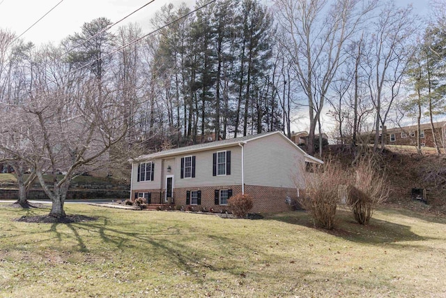 raised ranch with brick siding, a chimney, and a front yard