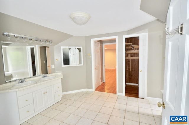 full bath featuring baseboards, tile patterned flooring, double vanity, and a sink