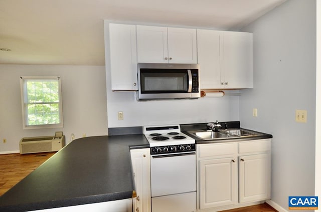 kitchen featuring white electric range oven, dark countertops, stainless steel microwave, and a sink