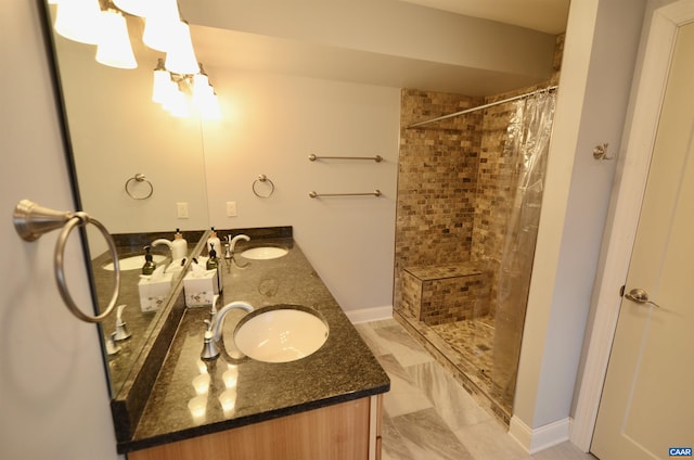 full bath featuring a sink, double vanity, marble finish floor, and a tile shower