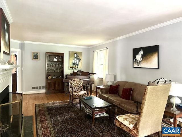 living room featuring visible vents, wood finished floors, a fireplace, and ornamental molding