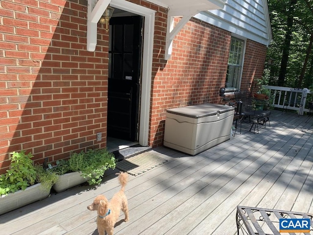 view of exterior entry featuring brick siding and a wooden deck