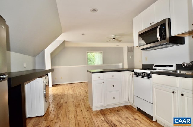 kitchen featuring white electric range oven, a peninsula, dark countertops, stainless steel microwave, and washer / clothes dryer