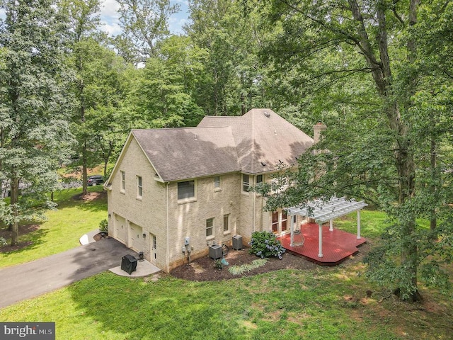  - view of property exterior with a wooden deck, driveway, a garage, roof with shingles, and a lawn