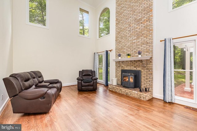  - living room featuring a high ceiling, wood finished floors, plenty of natural light, and a wood stove