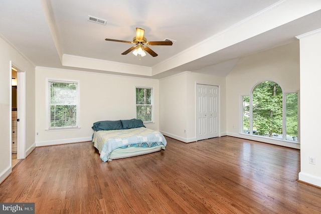  - bedroom featuring a raised ceiling, ornamental molding, wood finished floors, and multiple windows