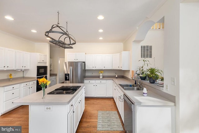  - kitchen featuring black appliances, ornamental molding, a kitchen island, white cabinets, and light countertops