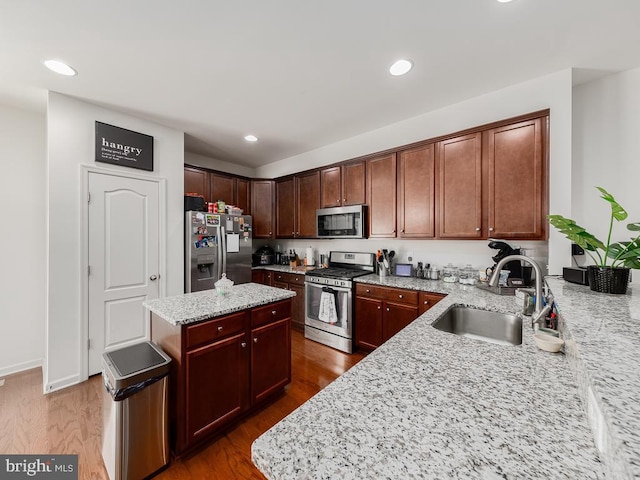 1420 Teagan Dr, Fredericksburg, VA 22408 - kitchen with stainless steel appliances, a sink, a center island, light stone countertops, and wood finished floors