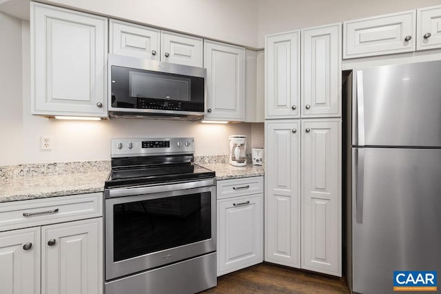 kitchen with light stone countertops, stainless steel appliances, dark wood-style floors, and white cabinets