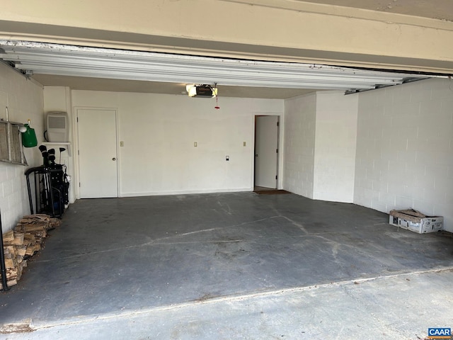 garage featuring concrete block wall and a garage door opener