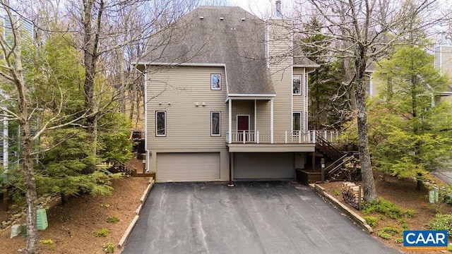 view of front of property featuring stairs, a deck, driveway, a garage, and a shingled roof