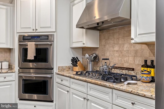 11135 Vanderbilt Cv, Spotsylvania, VA 22551 - kitchen featuring appliances with stainless steel finishes, range hood, backsplash, white cabinets, and light stone counters