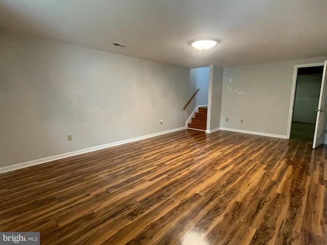 empty room featuring dark wood finished floors, stairs, and baseboards
