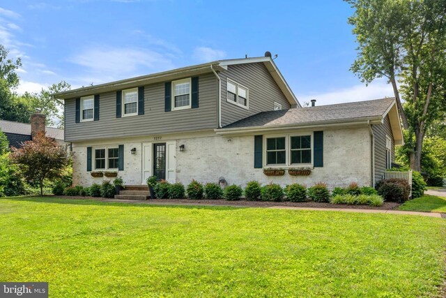  - view of front of home with a front yard and brick siding