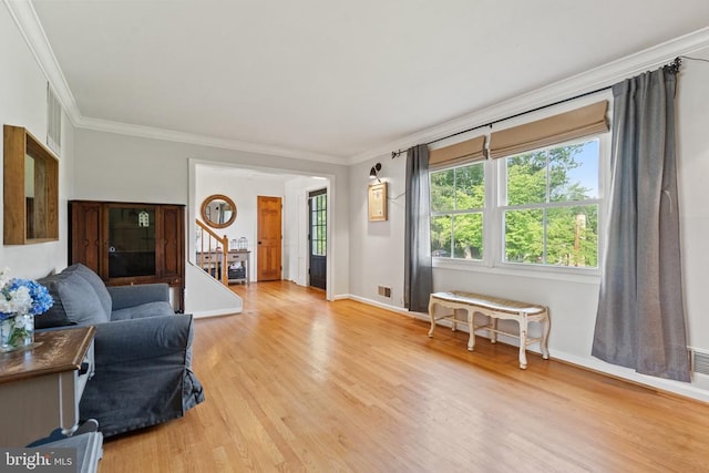  - living room with crown molding, light wood-style flooring, and stairway
