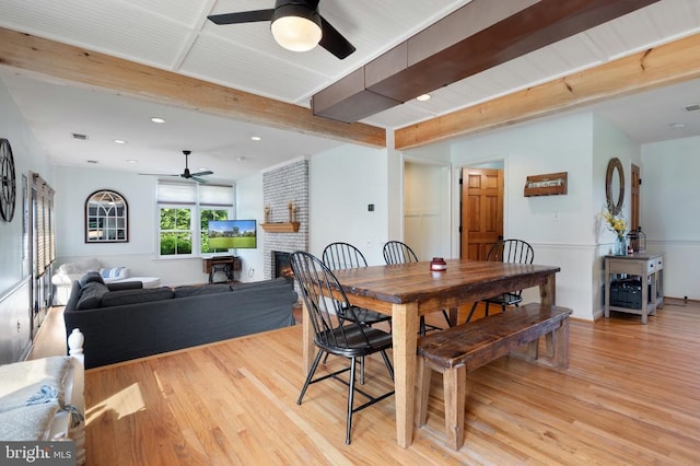  - dining space featuring a ceiling fan, beam ceiling, light wood-style flooring, a fireplace, and recessed lighting