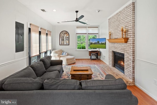  - living area with electric panel, wood finished floors, ceiling fan, a brick fireplace, and recessed lighting