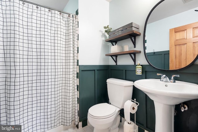  - full bath with curtained shower, a wainscoted wall, and tile patterned flooring