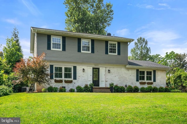  - colonial home featuring a front lawn and brick siding