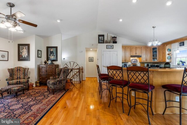 15103 Jenkins Hill Ln, Culpeper, VA 22701 - kitchen with vaulted ceiling, a breakfast bar area, ceiling fan, glass insert cabinets, and light wood-type flooring