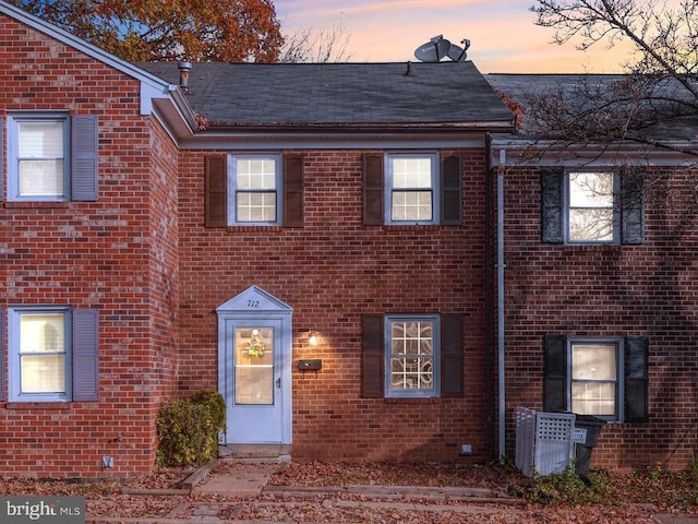 view of property with brick siding and a shingled roof