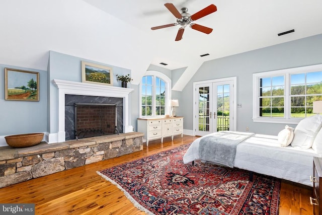 - bedroom featuring access to outside, vaulted ceiling, french doors, multiple windows, and wood finished floors