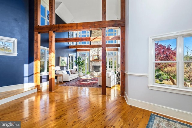  - foyer entrance featuring a towering ceiling, plenty of natural light, baseboards, and wood finished floors