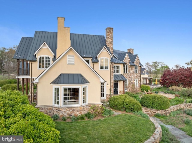  - back of property featuring a standing seam roof, metal roof, and a chimney