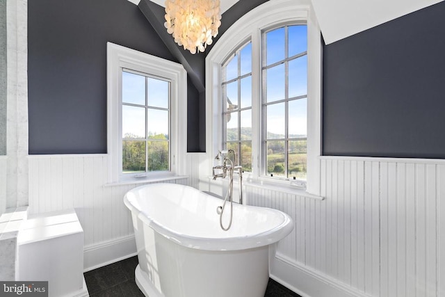  - bathroom with wainscoting, healthy amount of natural light, vaulted ceiling, and a soaking tub