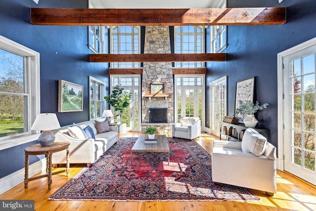  - living area with plenty of natural light, a fireplace, a towering ceiling, and beamed ceiling