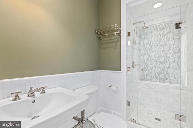  - bathroom with a sink, a shower stall, wainscoting, and toilet