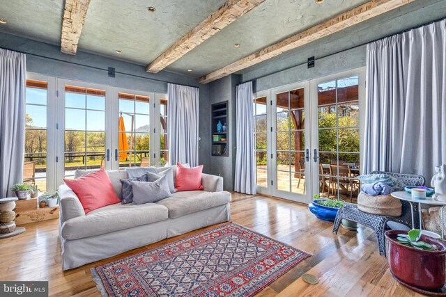  - living area featuring french doors, wood-type flooring, beamed ceiling, and plenty of natural light
