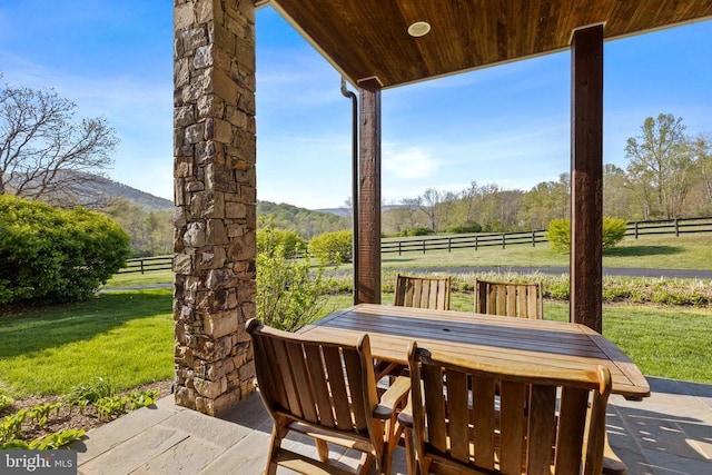  - view of patio with outdoor dining area, a mountain view, and a rural view