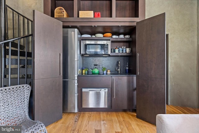 - bar area featuring stainless steel appliances, a sink, and light wood-style flooring