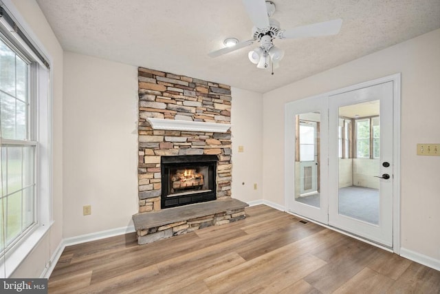 11810 Falcon Ridge Dr, Fredericksburg, VA 22407 - unfurnished living room featuring wood finished floors, a textured ceiling, a stone fireplace, ceiling fan, and baseboards