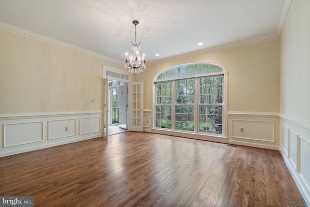  - empty room featuring a chandelier, crown molding, a decorative wall, and wood finished floors