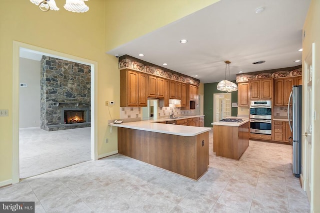  - kitchen with a peninsula, appliances with stainless steel finishes, a chandelier, and brown cabinetry