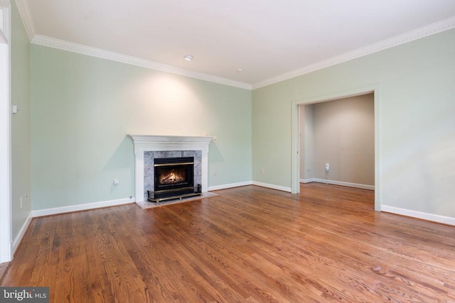  - unfurnished living room featuring a fireplace, crown molding, baseboards, and wood finished floors