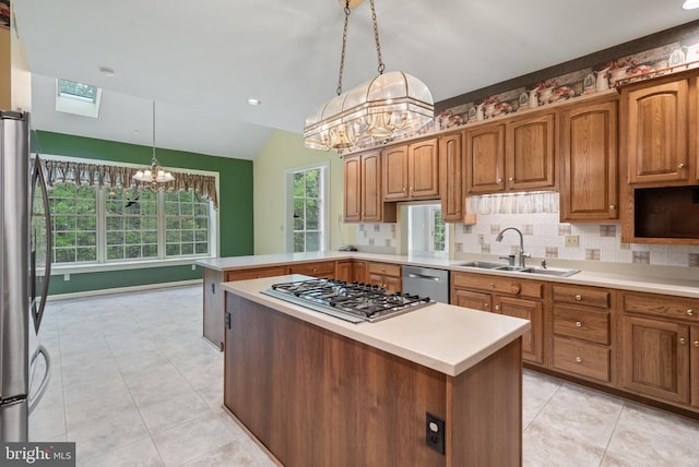  - kitchen featuring brown cabinets, a sink, vaulted ceiling with skylight, appliances with stainless steel finishes, and a chandelier
