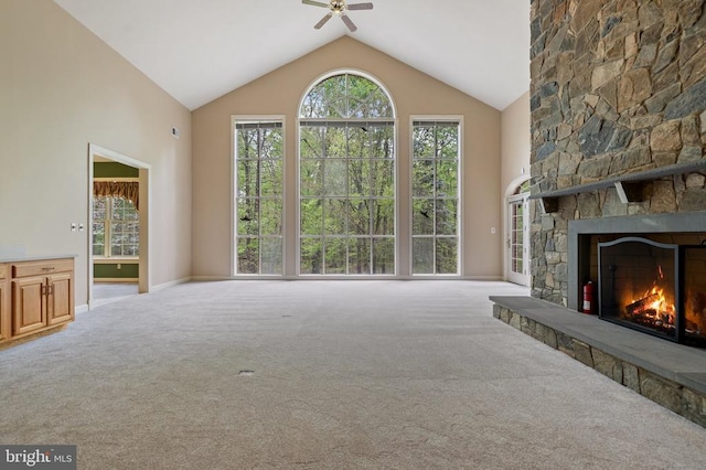  - unfurnished living room with high vaulted ceiling, carpet flooring, a ceiling fan, baseboards, and a stone fireplace
