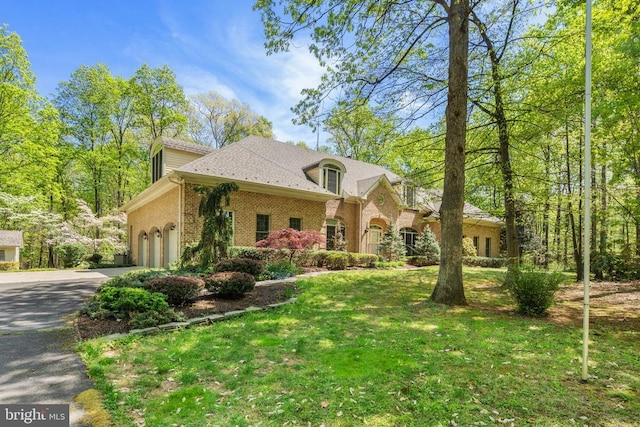  - view of front of property with a front yard, brick siding, driveway, and a garage