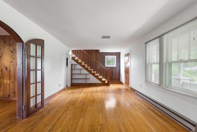 4056 E Point Rd, Elkton, VA 22827 - unfurnished living room featuring a baseboard heating unit, wood finished floors, baseboards, arched walkways, and stairway